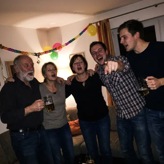 Freunde singen Arm in Arm auf einer Feier mit